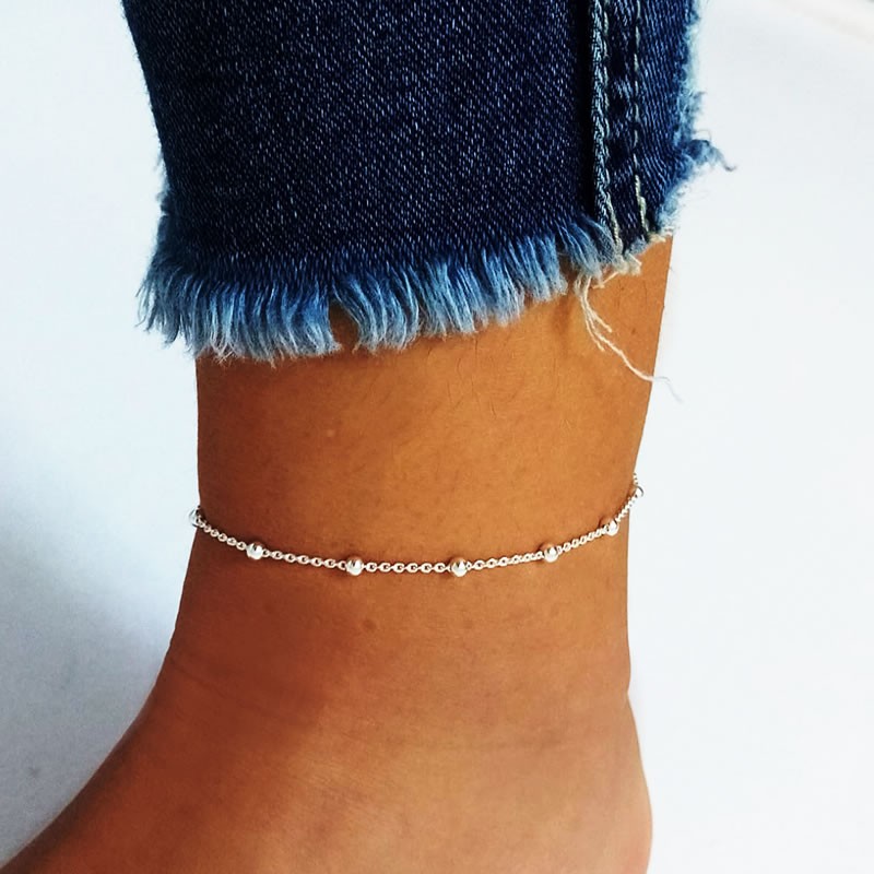 Silver bead anklet on ankle with jeans.