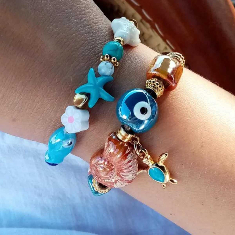 "Turtle Bay" bracelet with turtle, seashell, and evil eye charms in aquatic tones.